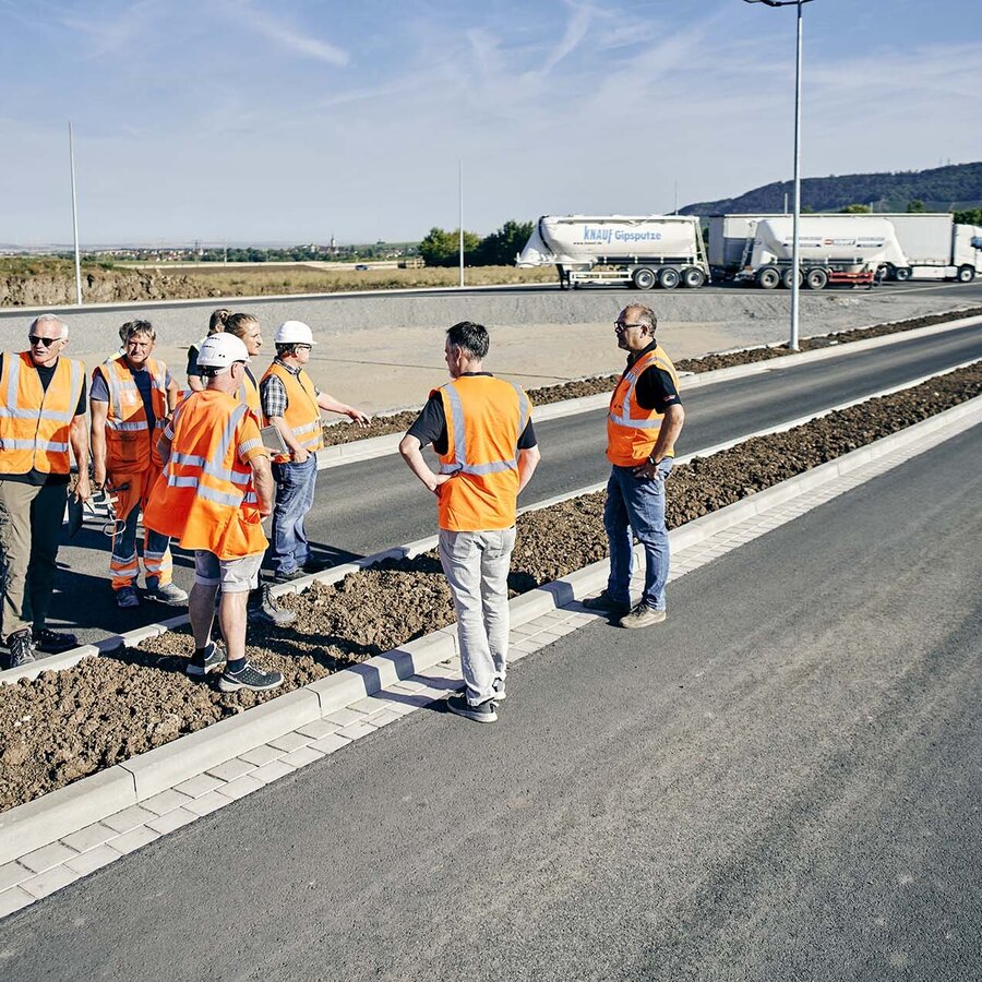 Ingenieure und Bauarbeiter bei Baubesprechung auf der Baustelle.